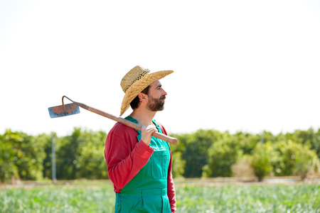Farmer man with hoe looking at his orchard field with hatの写真素材