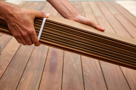 Ipe decking installation with carpenter hands holding tropical wood slats