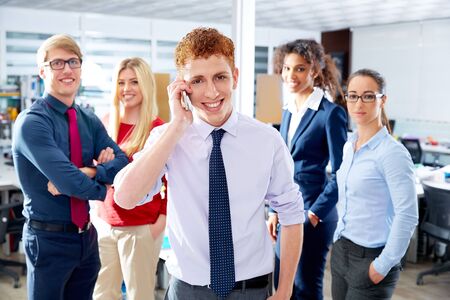 young executive talking phone in multi ethnic teamwork group as leader in officeの写真素材