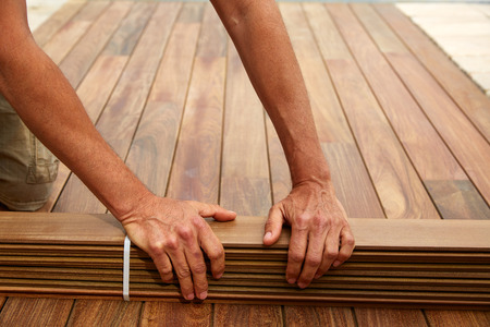 Ipe decking installation with carpenter hands holding tropical wood slatsの写真素材