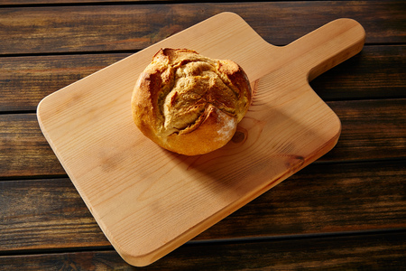 Bread round loaf on wooden board in rustic wood table