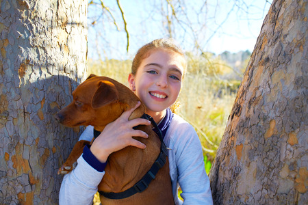 Autumn kid girl with pet dog relaxed in fall forest in Parc de Turia Valencia Spainの写真素材