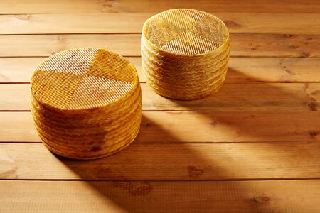 Manchego cheese from Spain in wooden table two whole piecesの写真素材