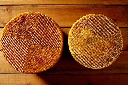 Manchego cheese from Spain in wooden table two whole piecesの写真素材