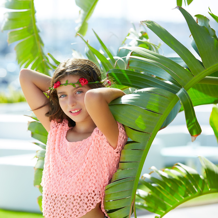 Brunette kid girl at banana tree leaves in bright day light in Mediterraneanの写真素材