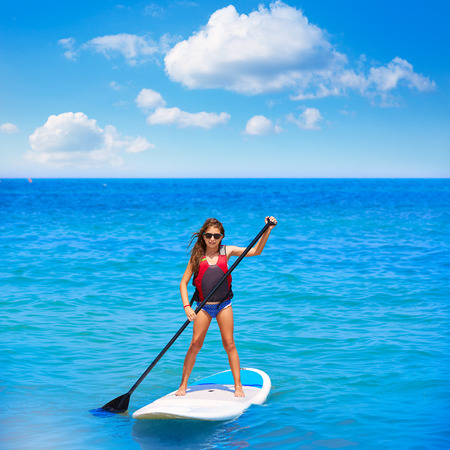 Kid paddle surf surfer girl with row in mediterranean beachの写真素材