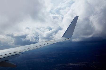 Aircraft wing in a cloudy stormy clouds sky flying