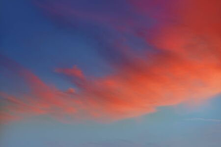 Red orange clouds in dramatic sunset blue sky
