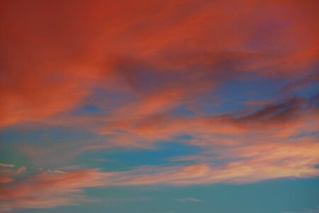 Red orange clouds in dramatic sunset blue sky