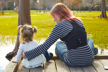Daughter and mother playing together in the park lake pierの写真素材