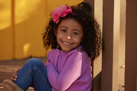 Happy toddler kid girl portrait in a park fence latin ethnicityの写真素材
