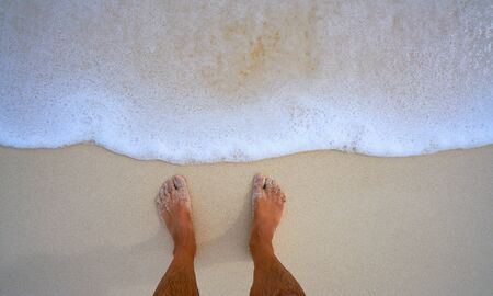 Tourist man feet in tropical white sand beach vacation concept