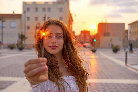 Teen girl with sparklers at sunset sky in the city