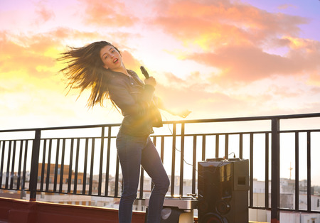 Band girl singing karaoke outdoor at roof terrace in the cityの写真素材
