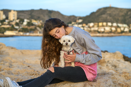 Girl playing with maltichon puppy dog in the beachの写真素材