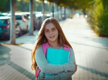 Blond kid student girl with notebook and backpack in the city back to school
