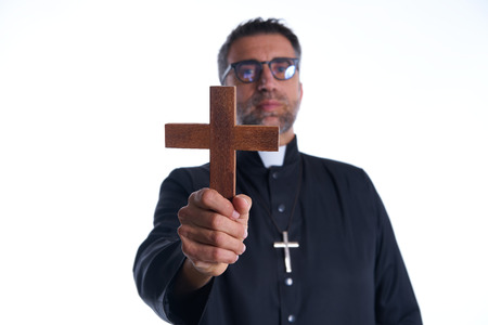 Priest holding cross of wood praying in foregroundの写真素材
