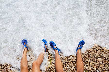 two kid girls legs in a beach foam shorePの写真素材