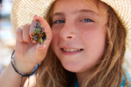 Blonk kid girl holding hermit crab closeupの写真素材
