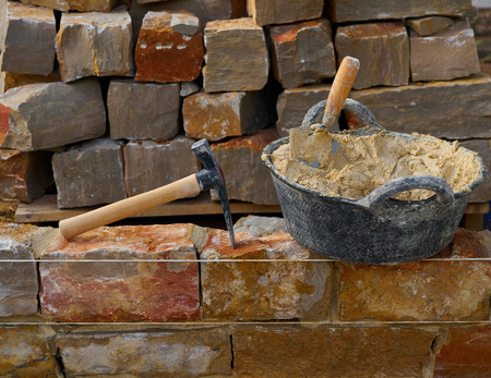 Masonry stone wall construction with mortar and brick hammer trowel tools DIYの写真素材