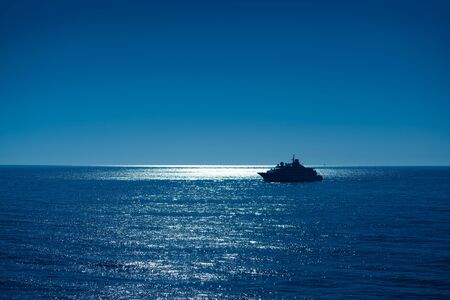 Sunset sunrise boat reaching Ibiza port with sun reflection in Mediterranean seaの写真素材