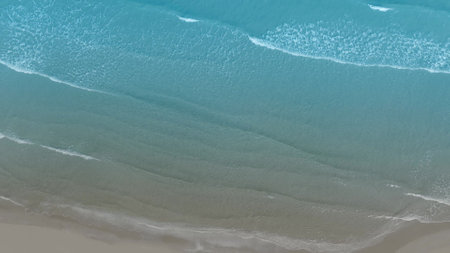 Aerial drone view tropical beach waves reaching sand shore coastlineの写真素材