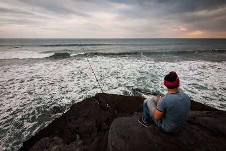 A Balinese man fishing on a cliffの写真素材
