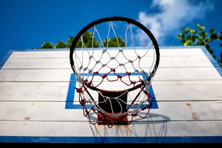 An old basketball backboard and rim under blue sky