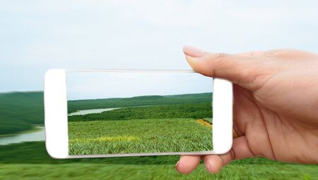 Woman make photo on smartphone, using phone in hand, travel nature river and mountain, Close up of women's hands holding mobilephone with  copy space screen.の写真素材