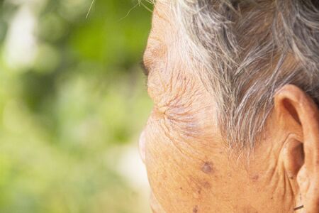 Close up The wrinkles of the face old woman asian  on green blurry background.