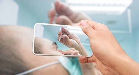 The patient is putting medication into the eye.conjunctivitis in  asian man and using eye drop treatment for eyeball and symptoms of pain and suffering use for health care solution or medicine product concept.の写真素材