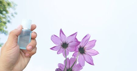 Close-up of male hand holding small plastic bottle of sanitizer antibacterial gel or oil lotion with...