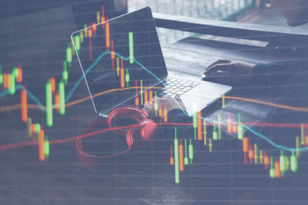 Businessman or broker looking at computer laptop analysing about stock market invest trading stocks graph analysis candle line in office room or coffee shop.の写真素材