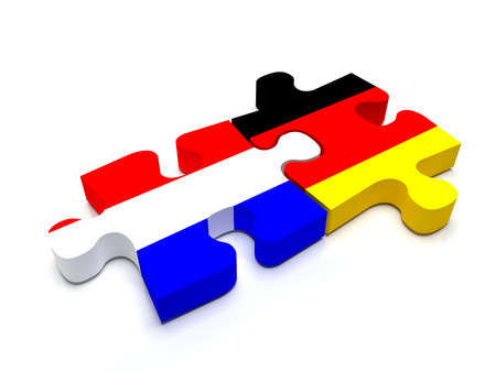 Puzzle pieces connect a piece containing the dutch flag and the german flag.の写真素材