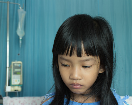 Portrait of a sick girl lying in a hospital bedの写真素材