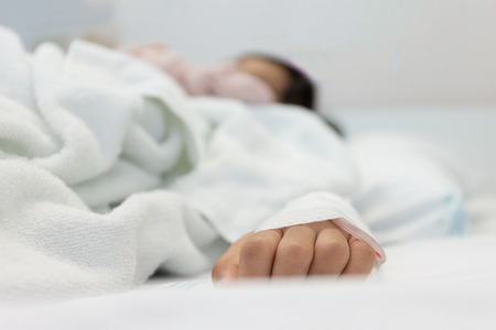 Patients hands of a girl lying on a hospital bed,dept of fieldの写真素材