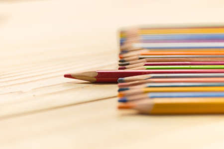 One  red pencil standing out from the other colors. on wood backgroundの写真素材