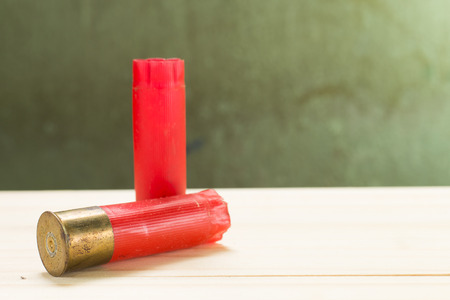 Through the use of shotgun shells lay on the wooden floor and green wall Background.の写真素材