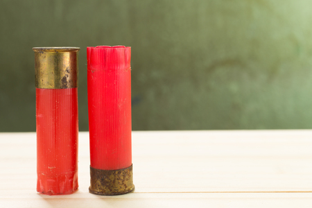 Through the use of shotgun shells lay on the wooden floor and green wall Background.の写真素材