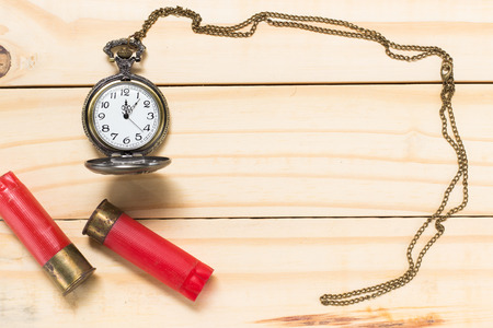 Red shotgun shell, antique clock placed on a wooden floor.の写真素材