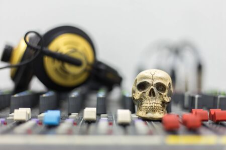Human skull resting on a sound mixer. Background on the mixer console and headphones.の写真素材