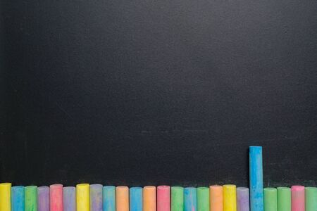 Group of colorful chalks on wood table with blackboard or chalkboard as background, concept for education, back to school.の写真素材