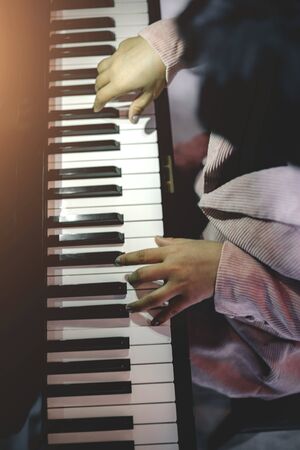 The young woman plays the piano at home in his own room after work to relax.の写真素材
