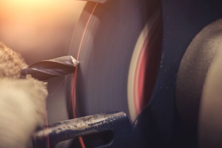 The hands of an engineering young man sharpening the drill bit.の写真素材