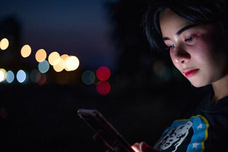 A girl playing social media with a bokeh backgroundの写真素材
