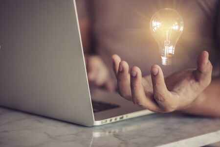 concept ideas with innovative technology and creativity./ A young businessman is holding a light bulb.の写真素材