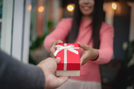 The young man's hand was holding a red gift box to the girl as a surprise.の写真素材