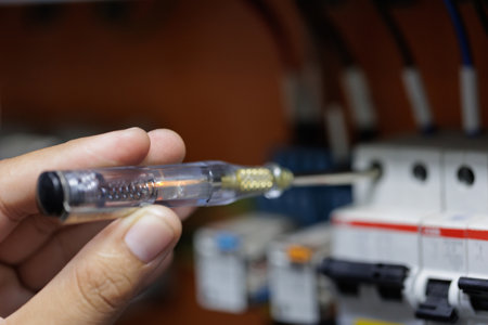 A close-up shot of a technician using a voltage tester pen to check for current in a circuit...