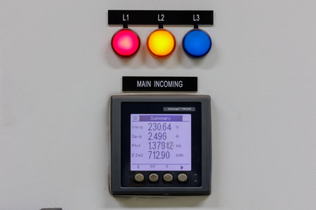 A close-up of a main incoming power monitoring panel. It features red, yellow, and blue indicator...
