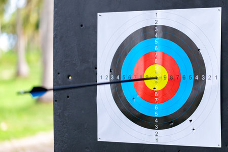 A close-up view of a paper archery target capturing the moment of impact as a single black arrow...